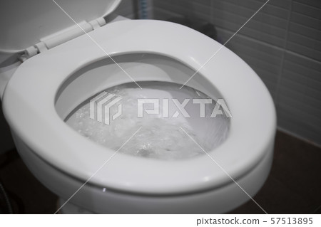 White hanging toilet seat on white toilet in the home bathroom with grey tiles. White hanging toilet seat on white toilet in the home bathroom with grey tiles. 57513895