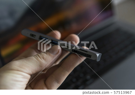 Man's hand holding The USB adapter under the Type-C connector for laptop. Multiport station for Man's hand holding The USB adapter under the Type-C connector for laptop. Multiport station for 57513967
