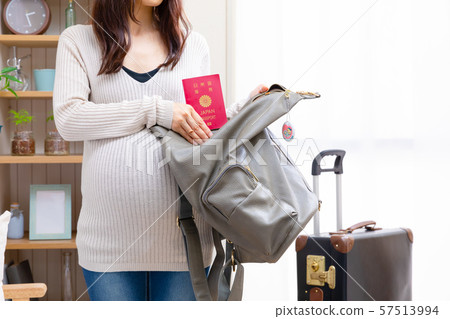 Pregnant woman putting passport in backpack 57513994