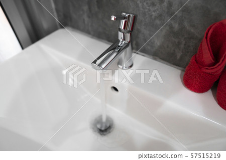 Running water from modern stainless steel faucet in white sink. Counter bathroom interior Running water from modern stainless steel faucet in white sink. Counter bathroom interior 57515219