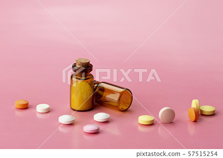 two brown glass bottles and different round coloured pills 57515254