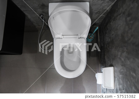 White hanging toilet seat on white toilet in the home bathroom with grey tiles in concrete style and 57515382