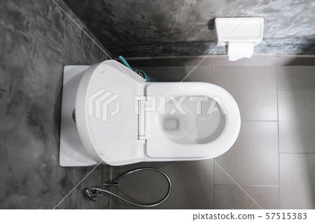 White hanging toilet seat on white toilet in the home bathroom with grey tiles in concrete style and 57515383