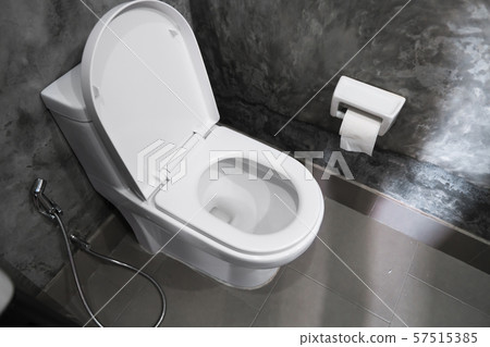 White hanging toilet seat on white toilet in the home bathroom with grey tiles in concrete style and 57515385