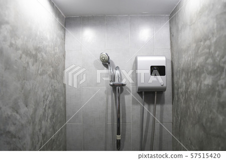 Instant tankless electric water heater installed on grey tile wall with input and output pipe/outlet Instant tankless electric water heater installed on grey tile wall with input and output pipe/outlet 57515420