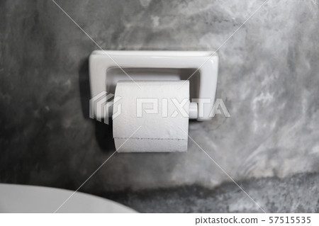 A white roll of soft toilet paper neatly hanging on a modern white holder on a concrete style A white roll of soft toilet paper neatly hanging on a modern white holder on a concrete style 57515535