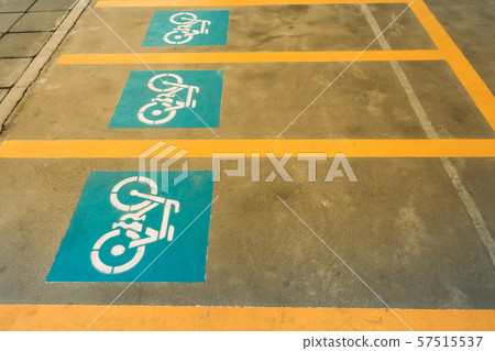 A white painting of a bicycle on the asphalt of the road that means mark of bicycle parking area. A white painting of a bicycle on the asphalt of the road that means mark of bicycle parking area. 57515537
