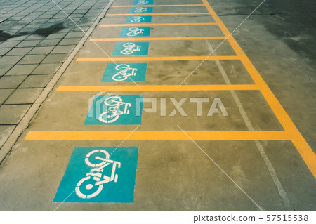A white painting of a bicycle on the asphalt of the road that means mark of bicycle parking area. A white painting of a bicycle on the asphalt of the road that means mark of bicycle parking area. 57515538