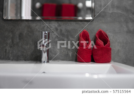 Modern stainless steel faucet with wash basin sink with a two red towels on it . Counter bathroom Modern stainless steel faucet with wash basin sink with a two red towels on it . Counter bathroom 57515564