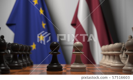 Flags of the EU and Latvia behind chess board. The first pawn moves in the beginning of the game Flags of the EU and Latvia behind chess board. The first pawn moves in the beginning of the game 57516603