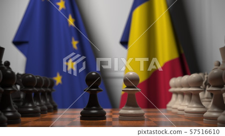 Flags of the EU and Romania behind chess board. The first pawn moves in the beginning of the game Flags of the EU and Romania behind chess board. The first pawn moves in the beginning of the game 57516610