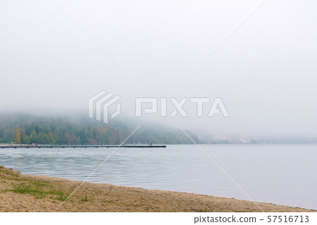 shore of an autumn lake in fog and a pier in the 57516713
