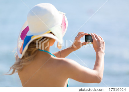 A girl shoots a video of the sea on a small camera. A girl shoots a video of the sea on a small camera. 57516924