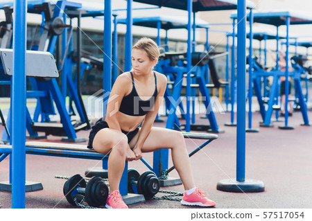 Profile view of a female athlete doing some tricep dips on a park bench. Profile view of a female athlete doing some tricep dips on a park bench. 57517054