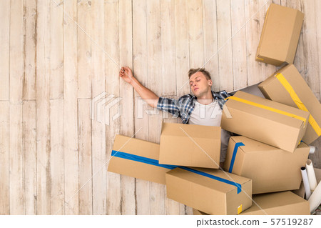 Young man lying on floor under boxes sleeping tired top view copy space Young man lying on floor under boxes sleeping tired top view copy space 57519287