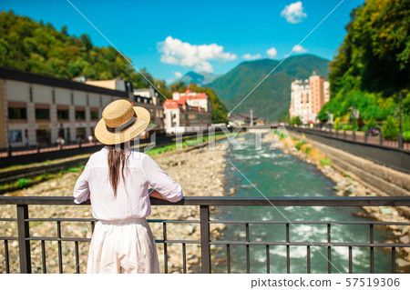 Happy girl at hat on the embankment of a mountain river in a European city. 57519306