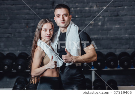 Young sporty couple guy and girl standing in gym. During this, the white scumbag is held on the neck 57519406