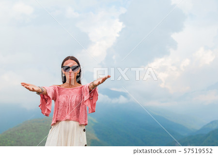Beautiful happy young woman in mountains in the background of fog 57519552