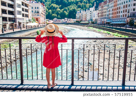 Little girl at hat on the embankment of a mountain river in a European city. Little girl at hat on the embankment of a mountain river in a European city. 57519955