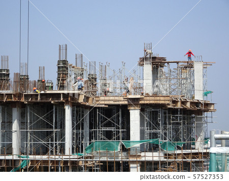 Construction workers working at height at the construction site. Using scaffolding as the temporary platform to work.  57527353