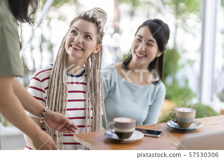 外國人和日本朋友從咖啡館服務員那裡接待並且微笑 57530306