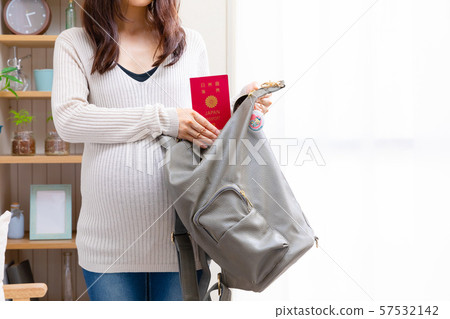 Pregnant woman putting passport in backpack Pregnant woman putting passport in backpack 57532142