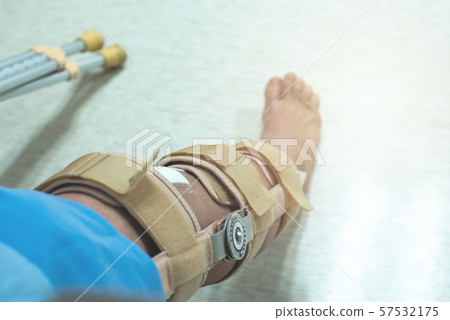 knee with knee brace support after surgery with walking stick of patient in hospital 57532175