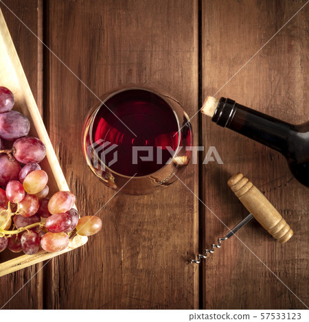 Wine Tasting. A photo of a red wine glass with a bottle, grapes, and a vintage corkscew, overhead 57533123