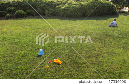 One year old boy escaping. Toys on the green lawn. One year old boy escaping. Toys on the green lawn. 57536008