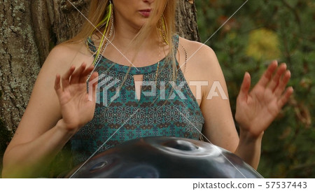 Beautiful young woman plays a hang in the autumn park 57537443