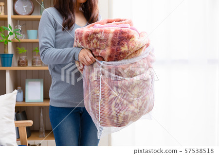 A woman putting a blanket into a laundry net 57538518