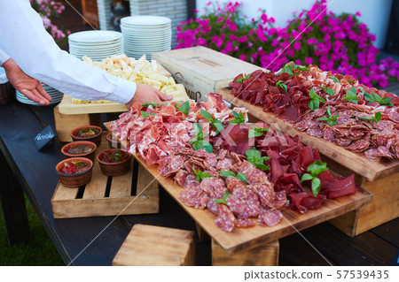 Plate and board with assortment of delicious deli meats on table Plate and board with assortment of delicious deli meats on table 57539435