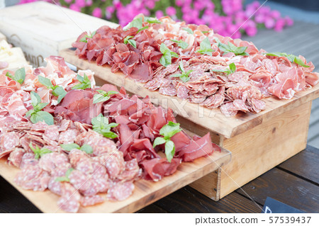 Plate and board with assortment of delicious deli meats on table Plate and board with assortment of delicious deli meats on table 57539437