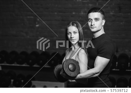 A sports woman is doing a muscular exercise. Photo muscle fitness model development with dumbbells A sports woman is doing a muscular exercise. Photo muscle fitness model development with dumbbells 57539712