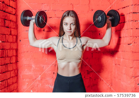 A sports woman makes an exercise weapon. Photo muscle fitness model development with dumbbells on a 57539736