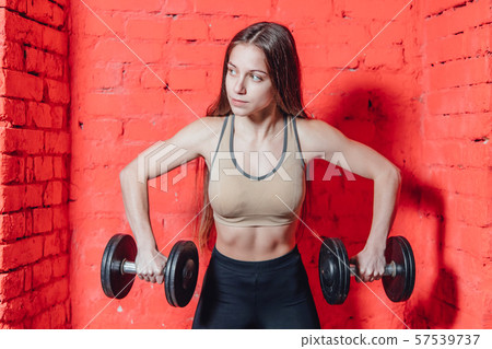 A sports woman makes an exercise weapon. Photo muscle fitness model development with dumbbells on a 57539737