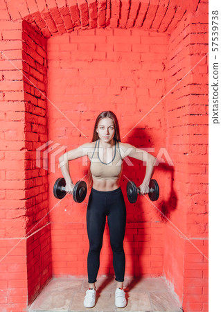 A sports woman makes an exercise weapon. Photo muscle fitness model development with dumbbells on a 57539738