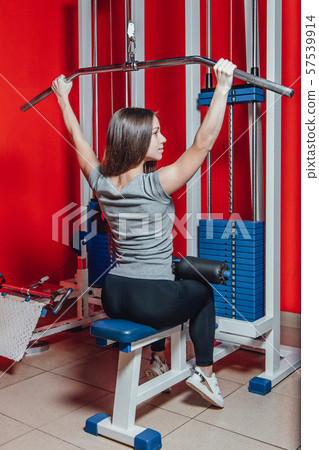 Beautiful sport girl is engaged on a simulator in the gym. Pretty girl with the beautiful tightened 57539914