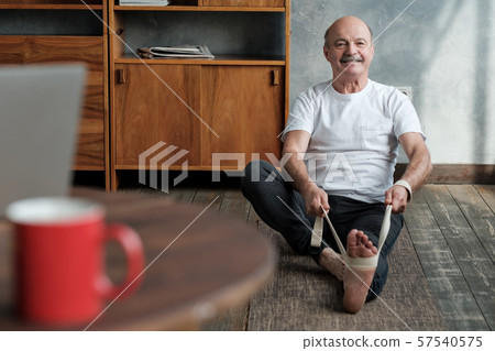 Senior hispanic man sitting in janushirshasana using belt Senior hispanic man sitting in janushirshasana using belt 57540575
