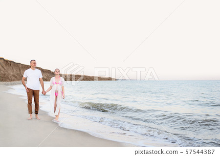 Young married couple walks along the sea coast. 57544387