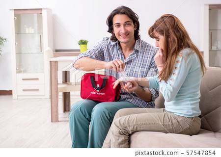 Young couple in first aid concept at home Young couple in first aid concept at home 57547854