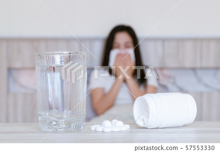 Flu medicine woman Infected With Cold the drug is placed on the table and a glass of water. 57553330