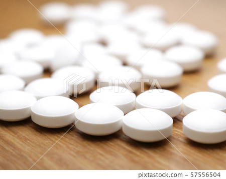 Supplement tablets spread on a wooden table 57556504