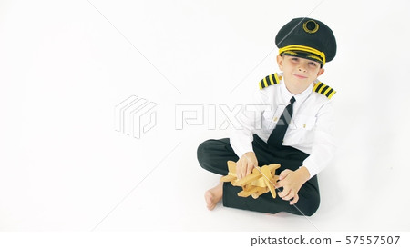 Boy wearing pilot's uniform plays with generic wooden toy plane Boy wearing pilot's uniform plays with generic wooden toy plane 57557507