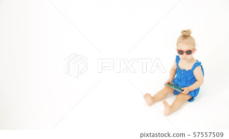 Serious baby girl wearing sunglasses watches unknown cartoon on a smartphone Serious baby girl wearing sunglasses watches unknown cartoon on a smartphone 57557509