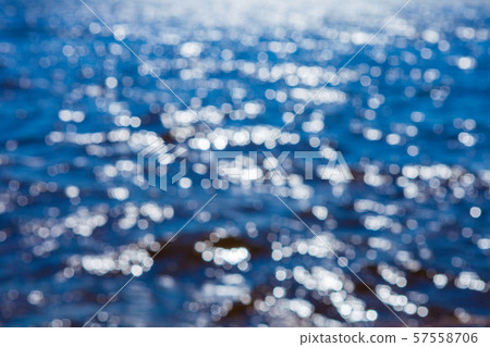 Blurred bokeh image of blue water with sun flare in the middle of the day. 57558706