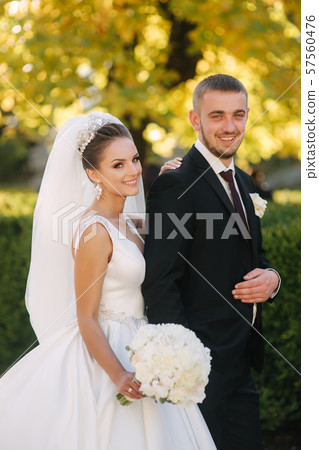 Beautiful bride with her husband in the park. Background of yellow tree. Happy couple 57560476