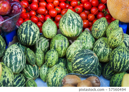 Ripe green small watermelons in the market. Fruits and vegetables on the counter. 57560494
