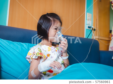 Sad asian child holds a mask vapor inhaler for treatment of asthma. Sad asian child holds a mask vapor inhaler for treatment of asthma. 57560961