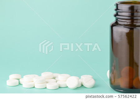 White round tablets scattered in front of glass White round tablets scattered in front of glass 57562422